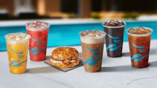 A summer-themed promotional banner featuring a lineup of cold beverages and a breakfast sandwich arranged on a white tabletop beside a swimming pool.