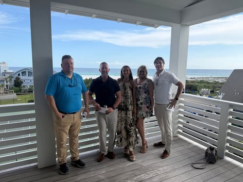 the five agents of the office all standing together on a patio with a railing behind them and blue skies