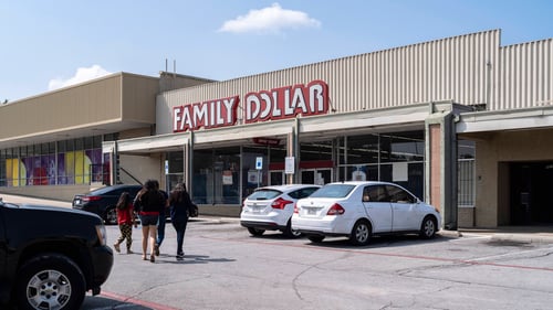 Family walking into Family Dollar with two white cars parked in front