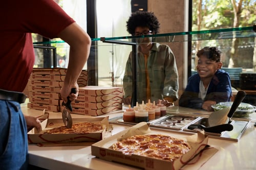 Guests watch as a member of the MOD Squad slices their personal pizza