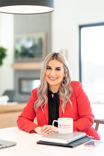 Agent Miriam sitting and smiling in black top and red jacket and white coffee cup