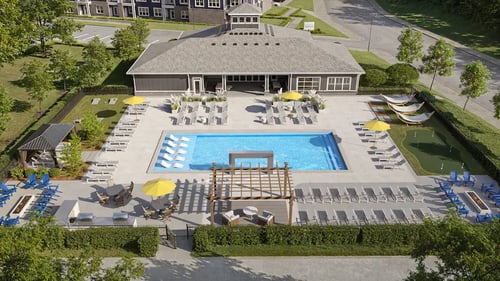 A large outdoor swimming pool area with sun loungers and a building in the background at The Remington, Lexington, 40511