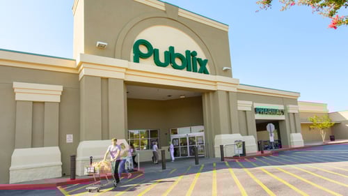 People with a shopping cart walking out of Publix