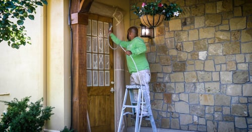 Professional Painter from LIME Painting stains the exterior of a wooden door to enhance its durability and vibrancy.