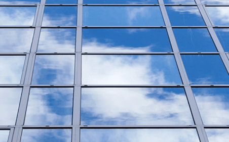 skyscraper windows reflecting blue sky and clouds
