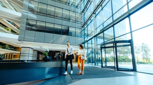 A man and woman walking through a large commercial buidling.