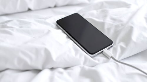 A picture of a smart phone on a bed.