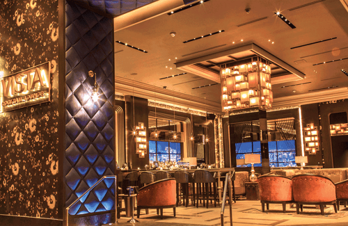 Go for the cocktails and stay for the LED “views” at the upscale VISTA Cocktail Lounge at Caesars Palace Las Vegas. Located in the center of the casino, enjoy casual drinks in this relaxed nightclub alternative. VISTA exudes a classic lounge feel and sophisticated atmosphere but with modern technology intertwined throughout the space. Located across from The Colosseum, Vista Cocktail Lounge makes a great pre-show meeting place. The real highlight is ordering a Manhattan drink while watching the crisp, observation deck-style vistas of the Manhattan cityscape displayed on screens.