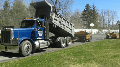 blue dump truck dumping stone