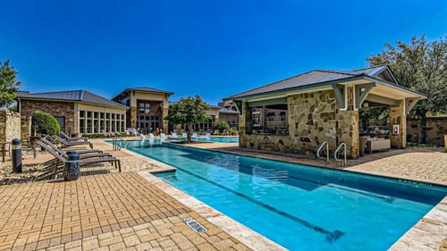 a swimming pool with chairs and a building in the background at Discovery at Craig Ranch, McKinney, TX, 75070