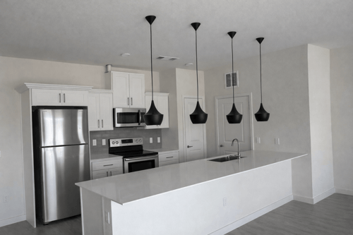 A kitchen with a refrigerator, oven, and microwave.
