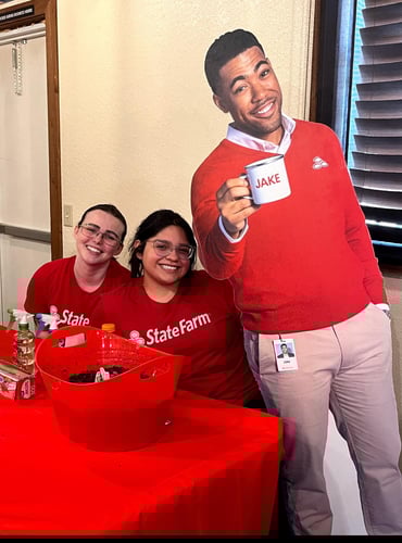Photo of two team members at a red table with the state farm mascot