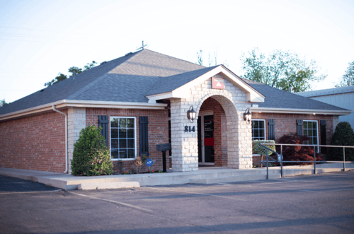 Brick building with green bushes and black shutters