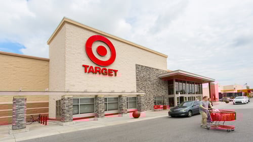 Black car passing person pushing shopping cart in front of Target at Victory Square shopping center