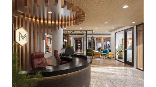 Modern apartment lobby featuring a curved black reception desk, vertical wood slats, and terrazzo flooring.