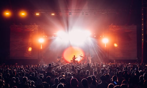Image of performer on stage with audience at a festival.
