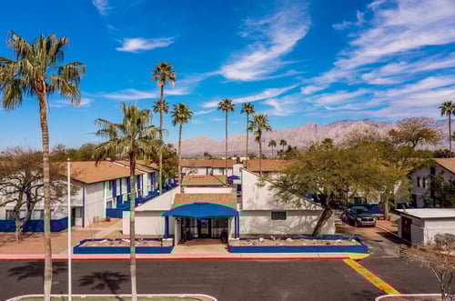 Main entrance of Midtown on Seneca Apartments in Palo Verde Tucson AZ with palm trees and mountain views.
