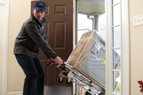 A Carrier dealer moves a furnace into a home as he performs an HVAC Installation
