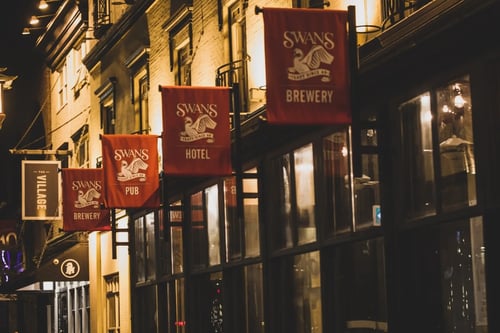 Exterior of Swans Pub Victoria BC at night with red Swans Brewery signs.