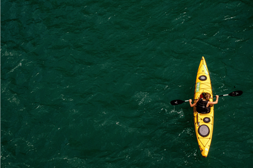 A kayaker in the middle of a body of water