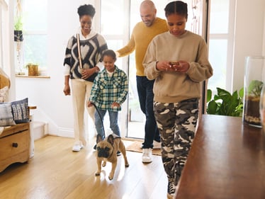 A family walking into their house with their dog.