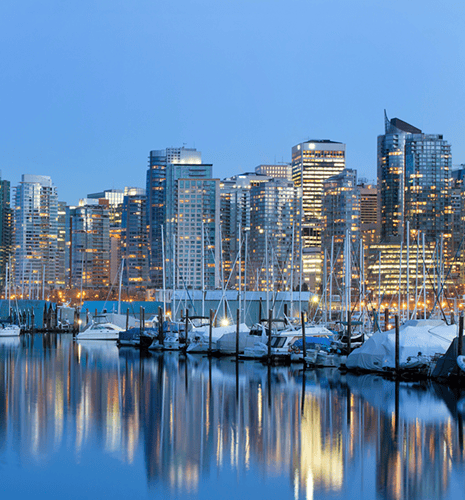 A city and boats at night reflecting off the water