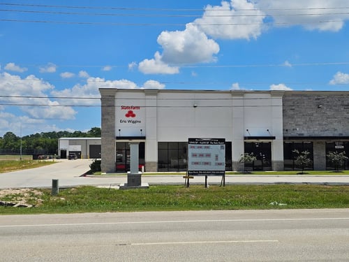 White and stone building with red State farm sign