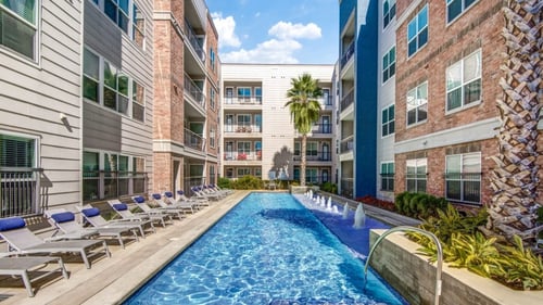 The swimming pool with lounge chairs in front of the building at Republic at Alamo Heights, San Antonio, TX