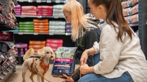 Myyjä esittelee koiranruokaa asiakkaalle