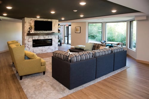 Modern apartment lounge with sofas, fireplace, TV, and large windows at Aspenwoods Apartments, Eagan, MN 55123