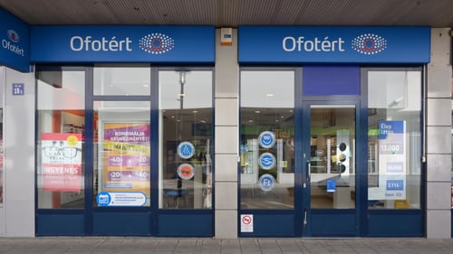 Ofotért üzlet bejárata Tatabányán, a Fő tér 18/A számnál, üvegportálos homlokzattal.