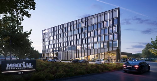 Modern facade of the M Social Hotel Sunnyvale building with glass windows and outdoor car parking at dusk