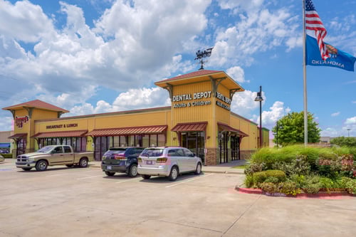 Exterior view of Dental Depot's Moore dental clinic with yellow walls and a red roof.
