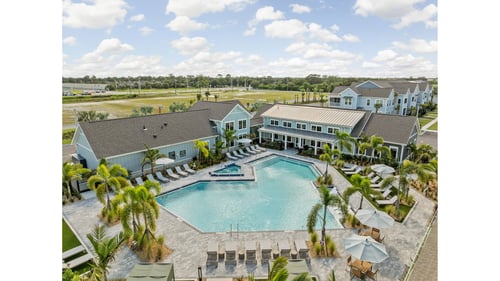 Large swimming pool with palm trees in front of a building at The Junction at Rockledge, Rockledge, FL 32955