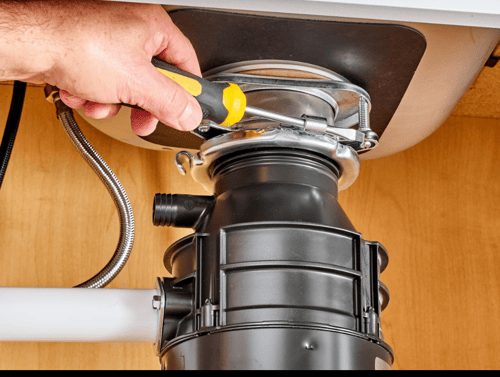 Plumber repairing garbage disposal under a kitchen sink