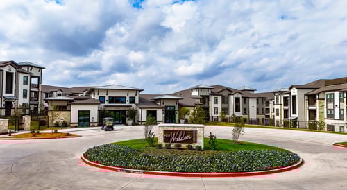 Exterior view of The Waldon apartment community in Melissa, TX, featuring modern architecture and a landscaped entrance.