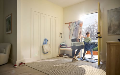woman and son leaving house with a pet in a crate