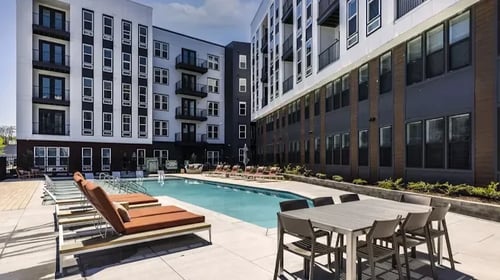 A pool area with chairs and a table in front of apartment buildings at Anchor Luxury Residences in Nashville, Tennessee