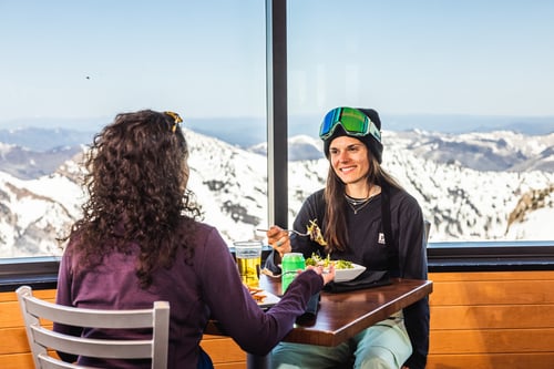 2 skiers eating at The Summit Restaurant. The highest on-mountain restaurant in Utah at Snowbird ski resort.