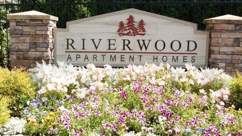 Welcoming sign with wildflowers surrounding at Riverwood Apartments at Kent, WA 98032