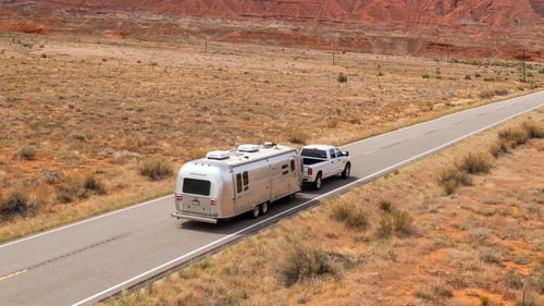 Truck towing an Airstream trailer on a desert road