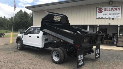 white dump truck in front of shop