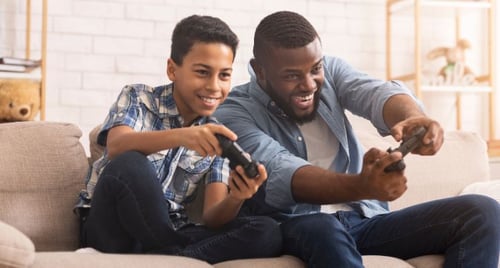 Financial education at home—father and son using video games to learn budgeting