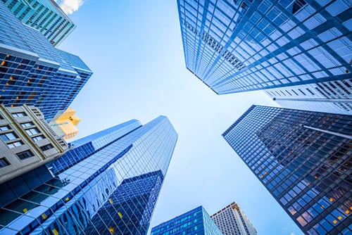 Bottom-up view of skyscrapers with a clear blue sky.