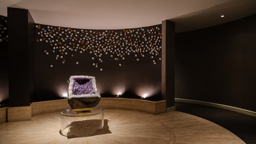 Tranquil spa hallway, featuring a large amethyst geode displayed on a lit pedestal, creating a serene, luxurious atmosphere