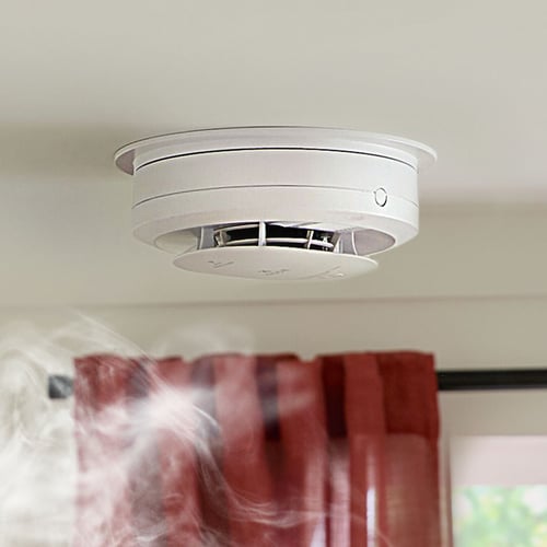 Smoke rises towards a smoke alarm.