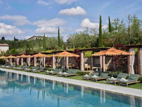 Poolside terrace with pergolas overlooking hills.