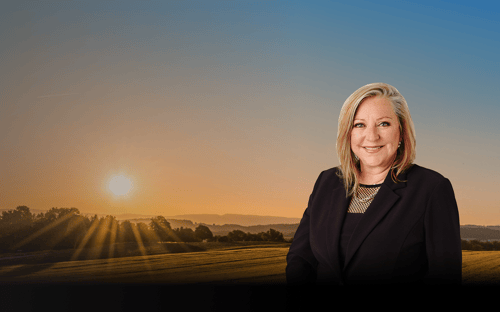 Brenda Miller in front of a large field illuminated by the rising run.