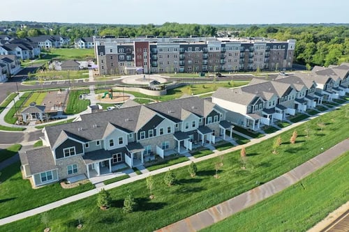 Row of modern two-story building overlooking a landscaped playground at Edison at Woodbury in Woodbury, MN